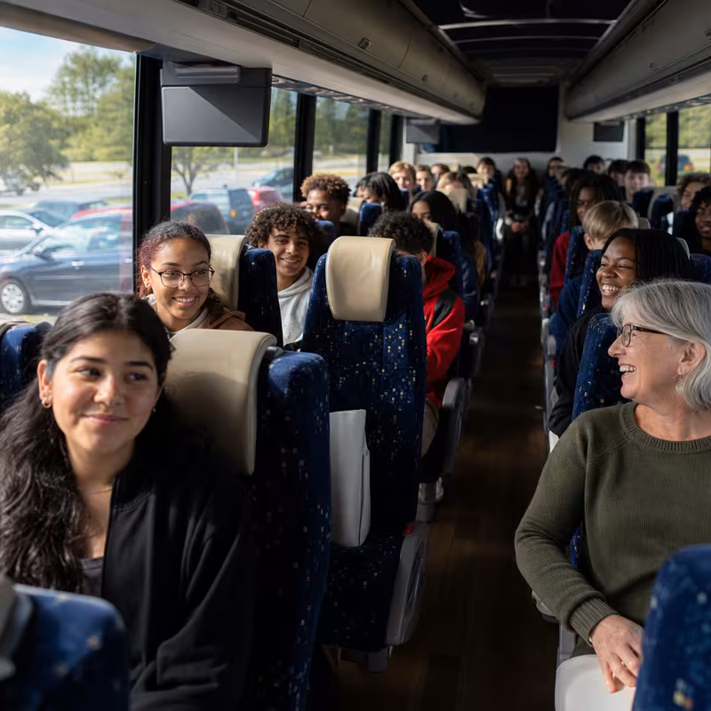 Group boarding a white charter bus for School Transportation transportation in Fort Wayne
